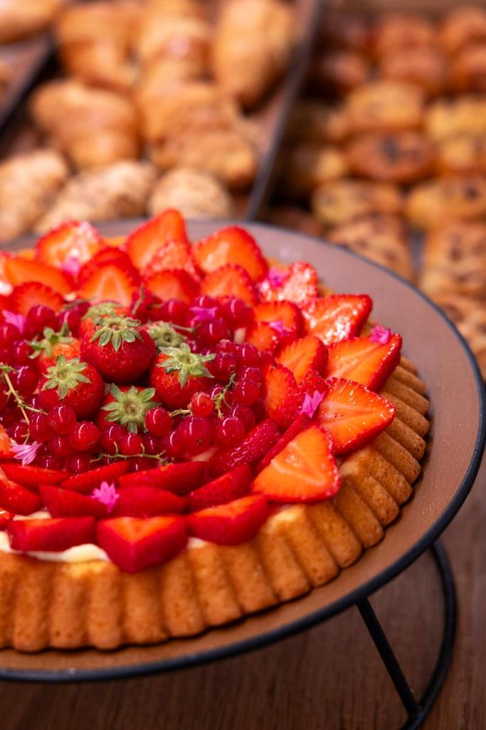 une tarte aux fruits sur une assiette avec des fraises dessus dans l'établissement Open Hotel, à Rimini