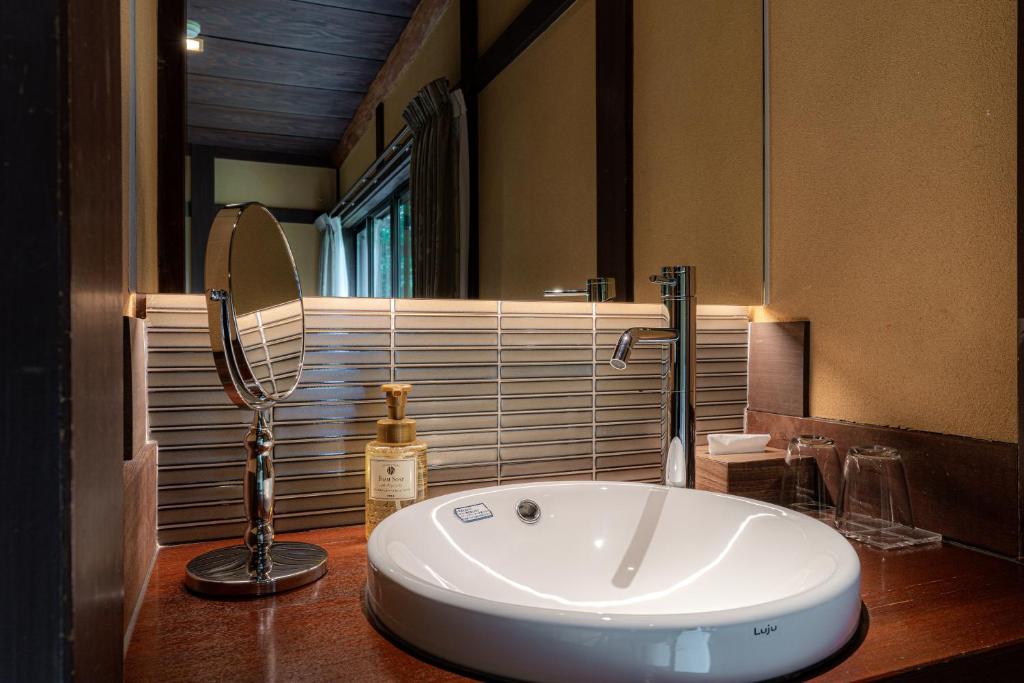 une salle de bain avec un lavabo et un miroir sur un comptoir dans l'établissement Japanese Ryokan Seryo, à Kyoto