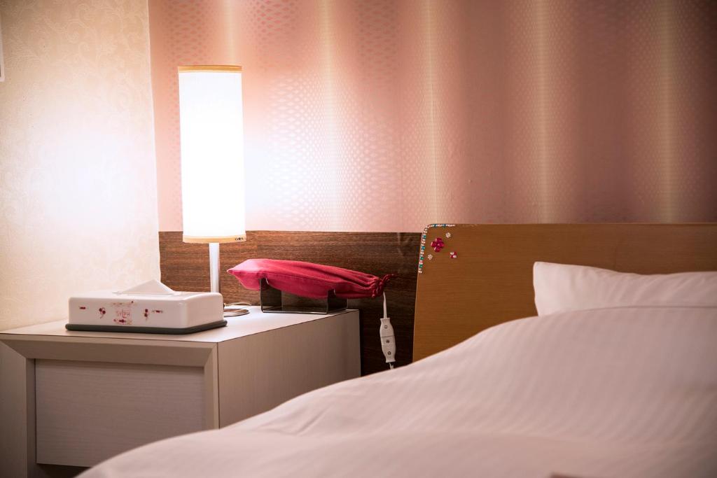 - une chambre avec un lit et une lampe sur une table de chevet dans l'établissement ホテル シルフ白兎海岸, à Tottori