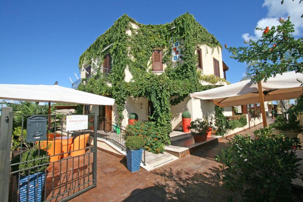 un bâtiment recouvert de lierre devant un bâtiment dans l'établissement Hotel Iride by Marino Tourist, à San Vito Lo Capo