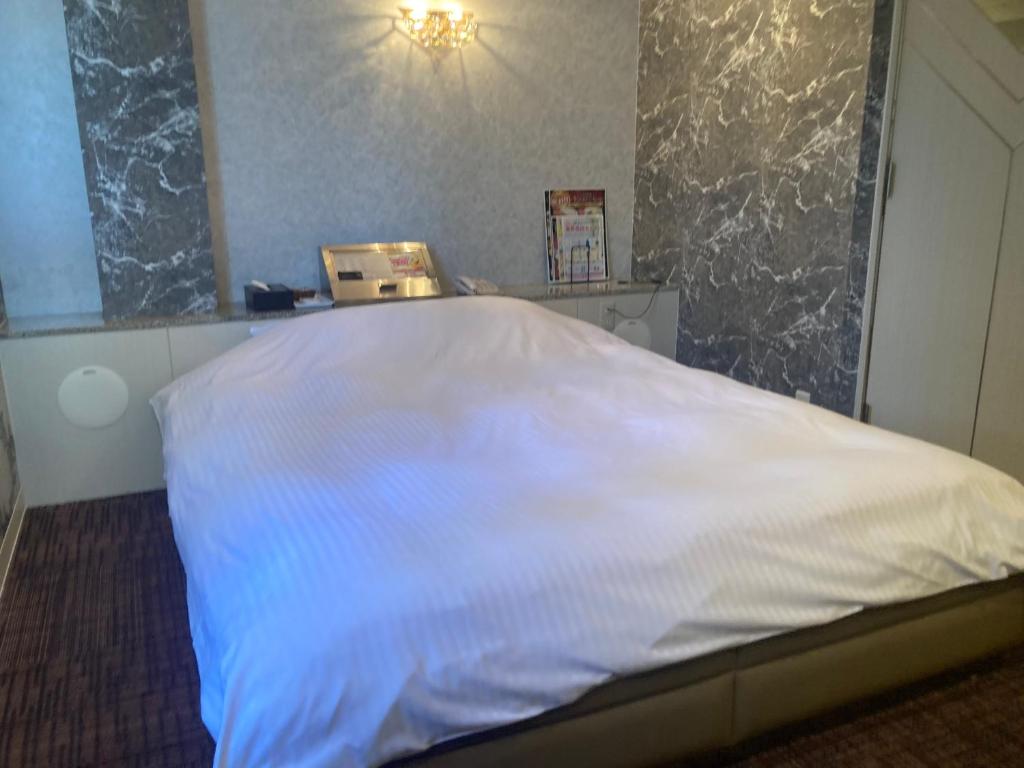 Ce lit se trouve dans un dortoir doté d'un couvre-lit blanc. dans l'établissement ホテルキャンパス, à Osaka