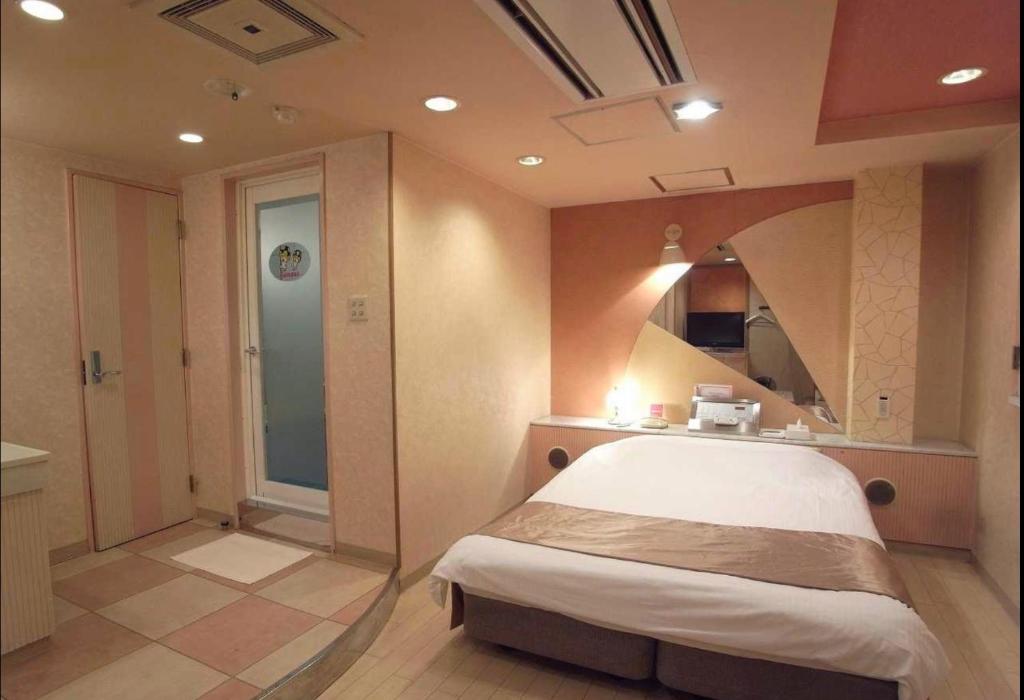une chambre avec un lit et une salle de bains avec un miroir dans l'établissement ホテルキャンパス, à Osaka
