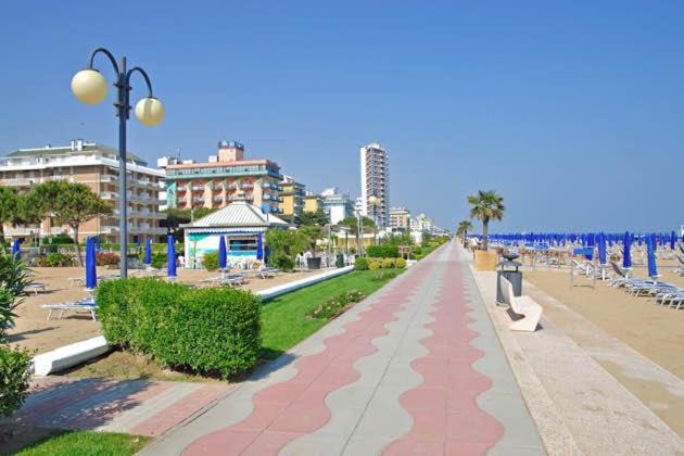 une personne marchant sur un trottoir à côté d'une plage dans l'établissement Residence Moresco, à Lido di Jesolo