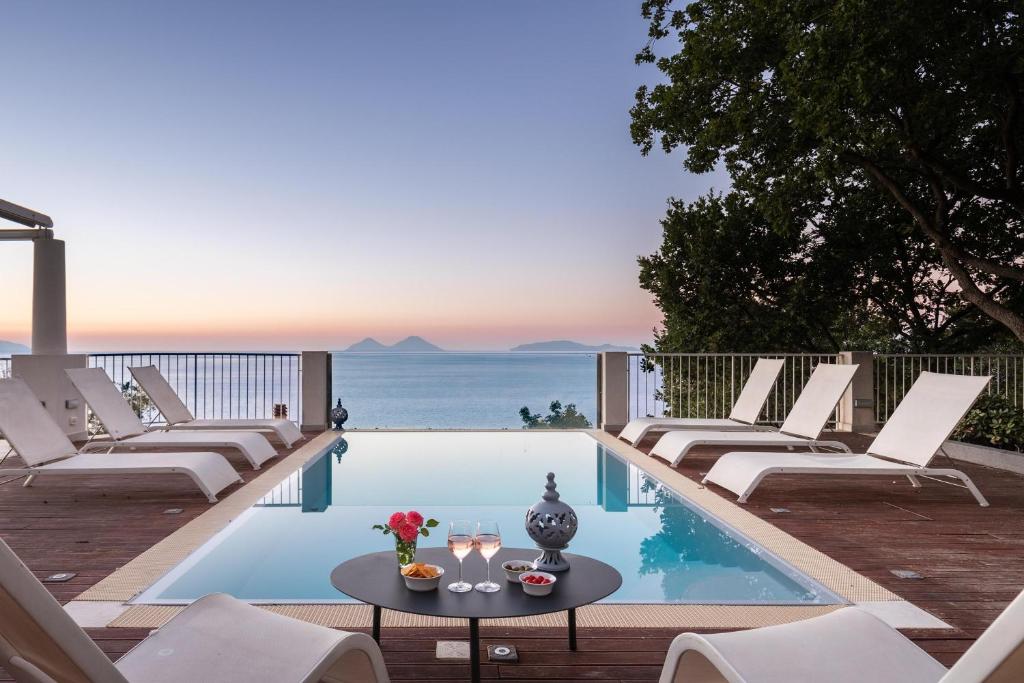 - une piscine avec des chaises et une table offrant une vue sur l'océan dans l'établissement Villa Stellata, à Naso