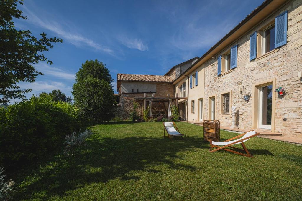 une maison dotée d'une cour avec deux chaises devant elle dans l'établissement tHE Timeless Villa - Natural Bio Pool in Monferrato, à Castellino