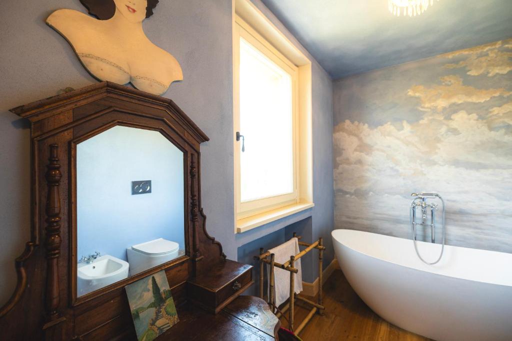 une salle de bain avec une baignoire et un miroir dans l'établissement tHE Timeless Villa - Natural Bio Pool in Monferrato, à Castellino