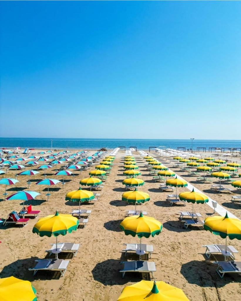 un tas de parasols et de chaises sur une plage dans l'établissement Beach Hotel Clerice, à Rimini