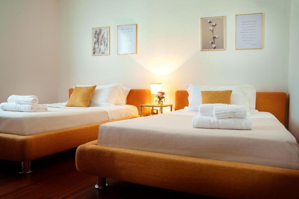 - 2 lits dans une chambre blanche et orange dans l'établissement Villa Nichil, à Tricase