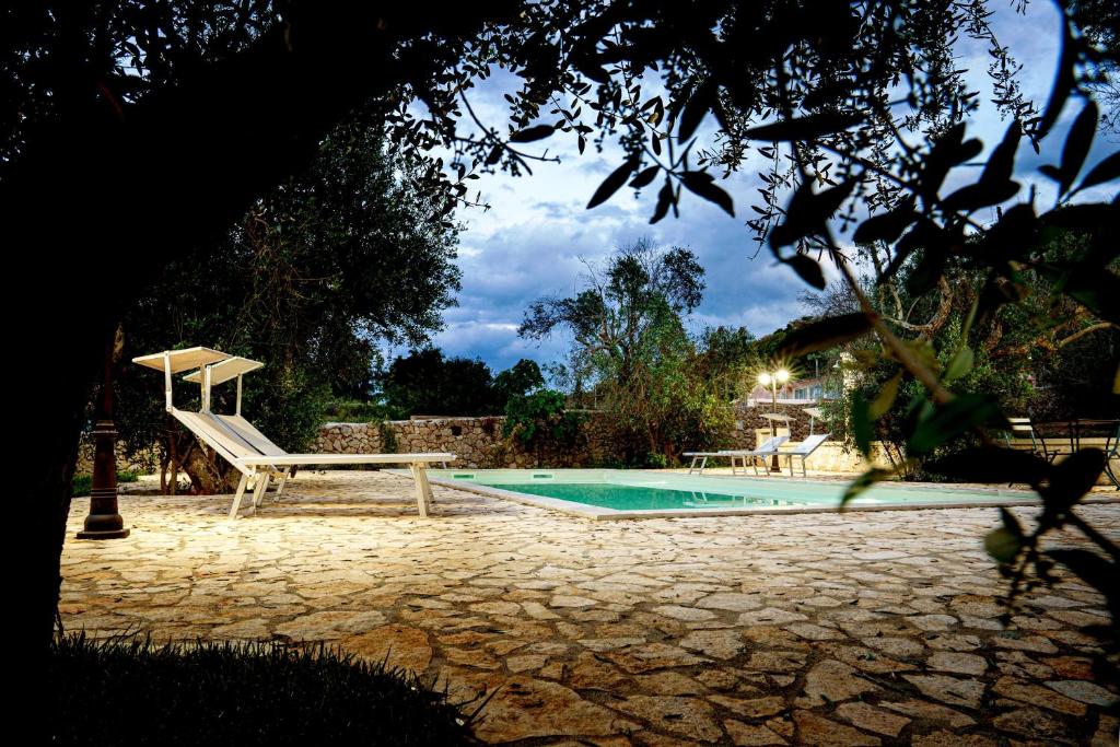 une piscine avec un banc à côté d'un banc dans l'établissement Villa Nichil, à Tricase