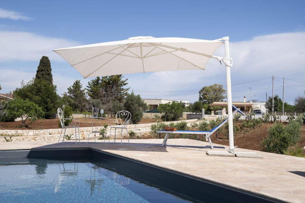 - un parasol blanc à côté de la piscine dans l'établissement filìa ϕιλία, à Serranova