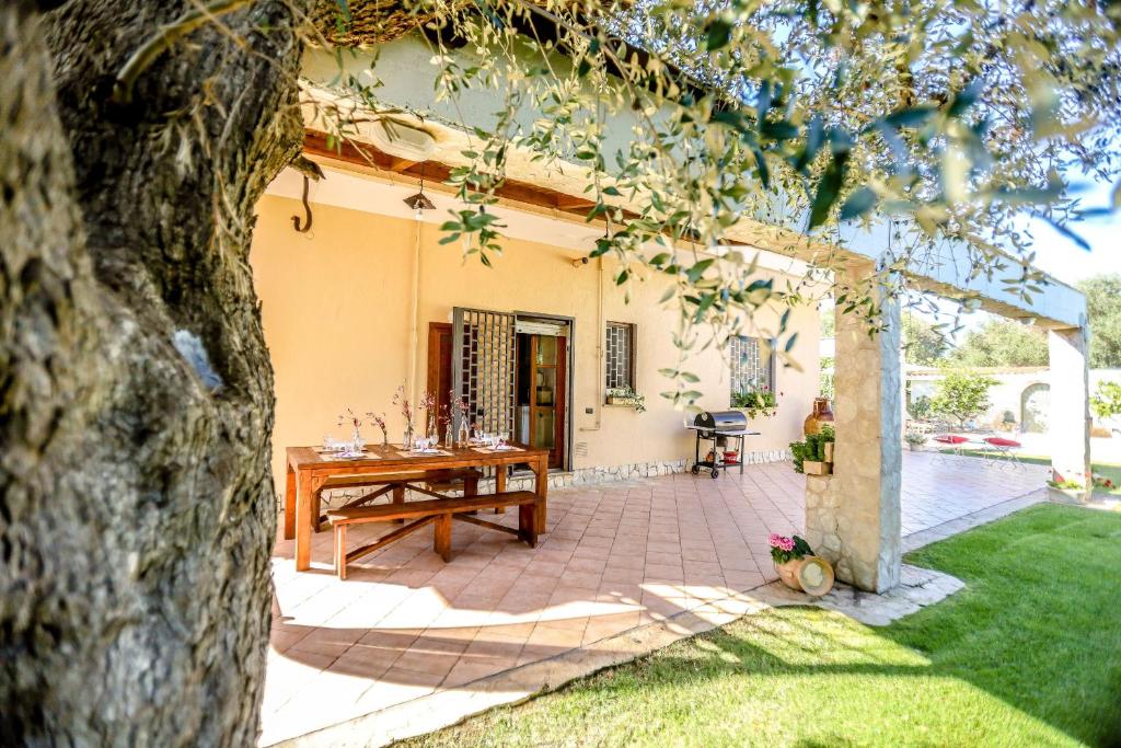 une terrasse avec une table en bois devant une maison dans l'établissement Villa indipendente con piscina privata by Pugliadamare, à San Michele Salentino