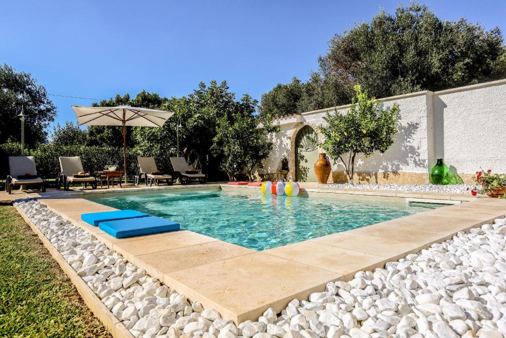 une piscine entourée de rochers et d'un parasol dans l'établissement Villa indipendente con piscina privata by Pugliadamare, à San Michele Salentino