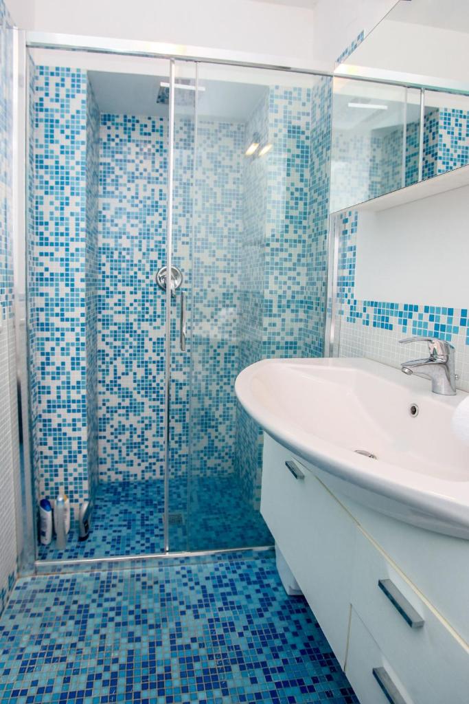 une salle de bain avec un lavabo et une douche avec du carrelage bleu dans l'établissement Villa Caraitria, à Martina Franca