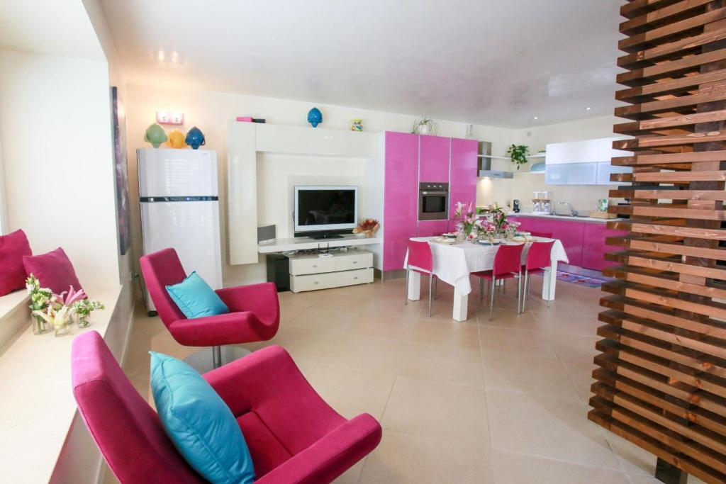 un salon avec des chaises roses et une salle à manger dans l'établissement Villa Caraitria, à Martina Franca