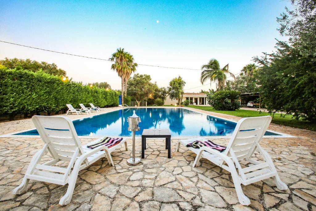 deux chaises et une table à côté d'une piscine dans l'établissement Villa con parco e piscina, à San Michele Salentino