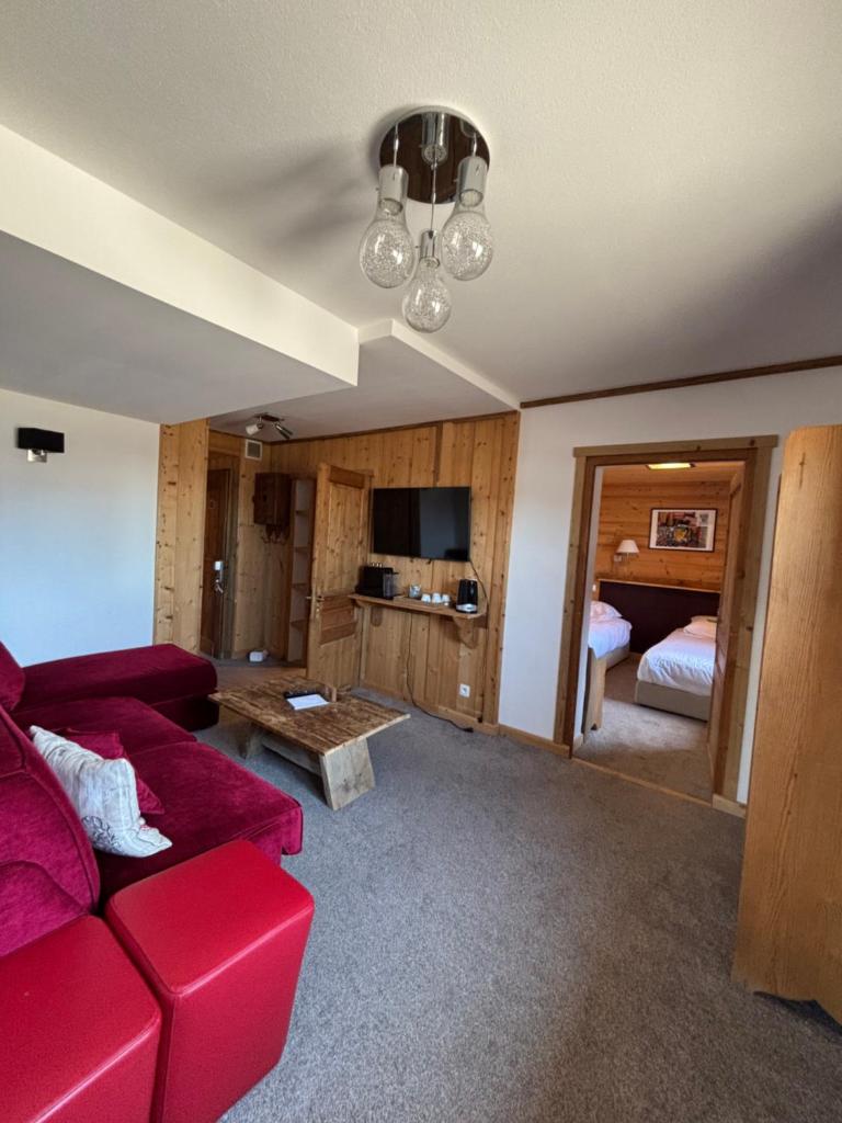 un salon avec un canapé rouge et une chambre dans l'établissement Chalet Hôtel du Mont-Charvin & Spa, à Crest-Voland