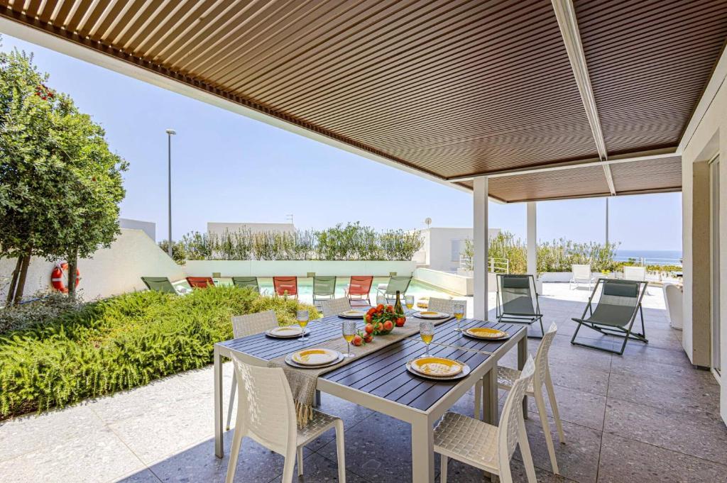 un patio avec une table et des chaises sur un patio dans l'établissement Villa Brezza Marina by Villa Plus, à Marina di Ragusa