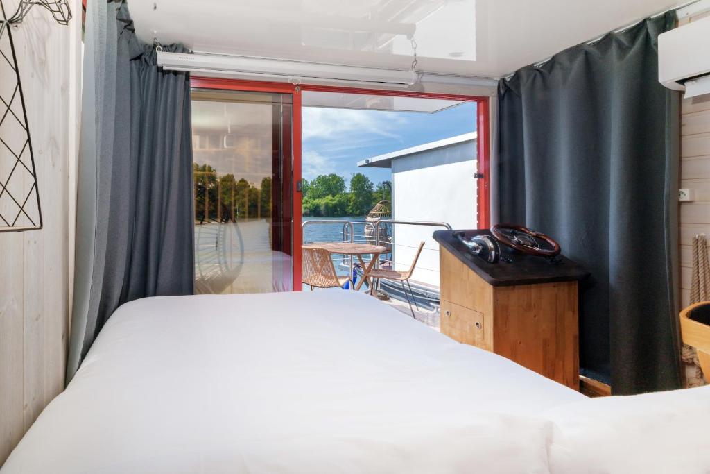 une chambre avec un lit et un balcon dans l'établissement L'Escale Royale Saint-Martin-la-Garenne Port Ilon - Seine - Giverny, à Saint-Martin-la-Garenne