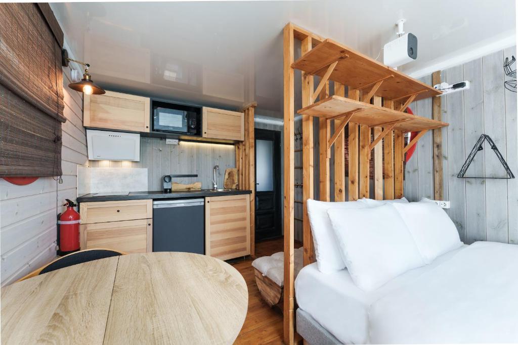 une petite maison avec une table et une cuisine dans l'établissement L'Escale Royale Saint-Martin-la-Garenne Port Ilon - Seine - Giverny, à Saint-Martin-la-Garenne