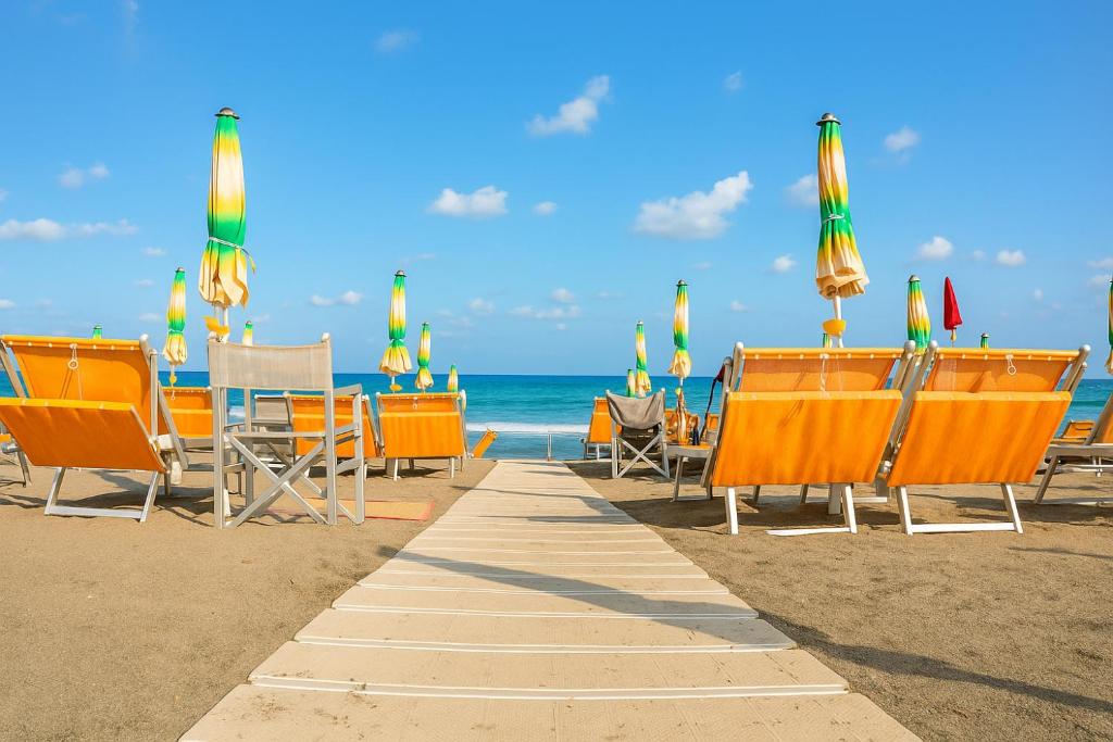 - une rangée de chaises et de parasols sur la plage dans l'établissement Hotel Mediterranea, à Loano