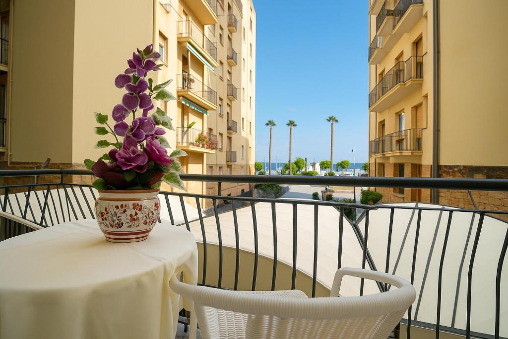un vase de fleurs violettes assis sur une table sur un balcon dans l'établissement Hotel Mediterranea, à Loano