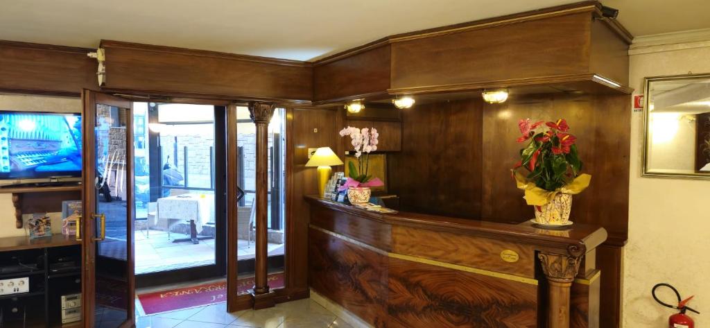 un hall d'entrée avec un mur en bois avec des fleurs dans un vase dans l'établissement Hotel Mediterranea, à Loano