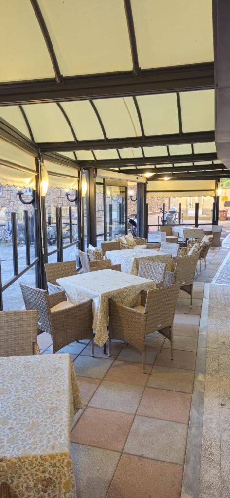 un restaurant avec des tables et des chaises blanches et des fenêtres dans l'établissement Hotel Mediterranea, à Loano