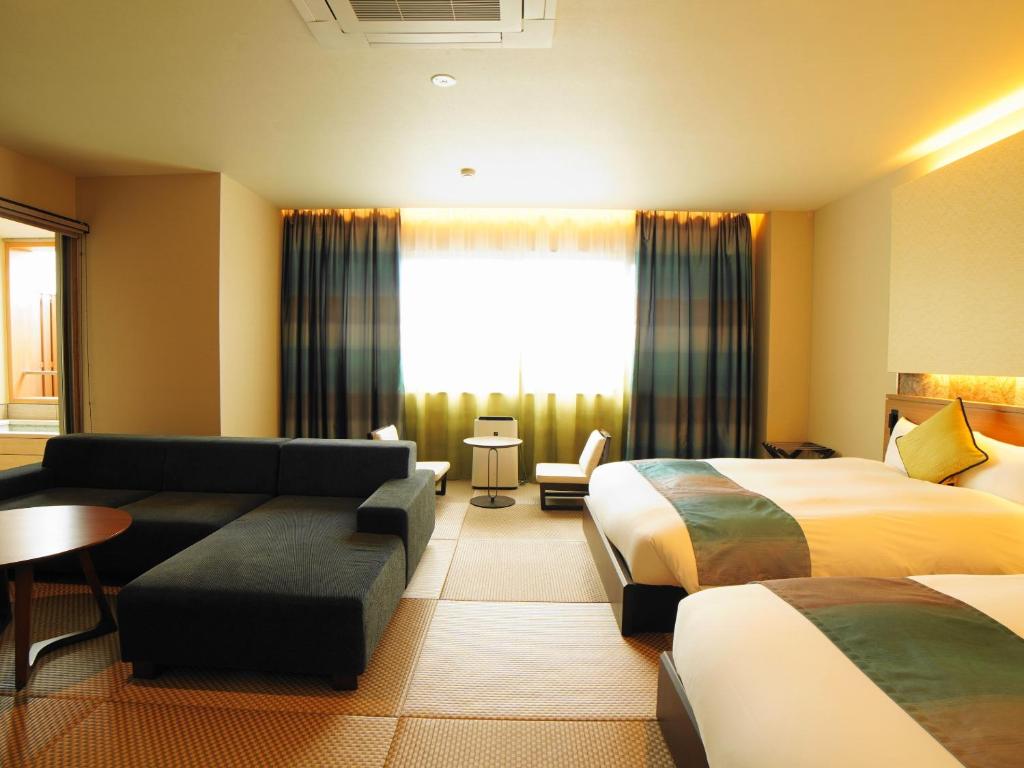 une chambre d'hôtel avec deux lits et un canapé dans l'établissement ジュラシック スパ &リゾート くつろぎの宿 樹楽, à Toon