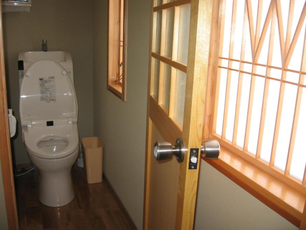 La salle de bains est pourvue de toilettes et d'une porte ouverte. dans l'établissement Yudanaka Yasuragi, à Yamanouchi