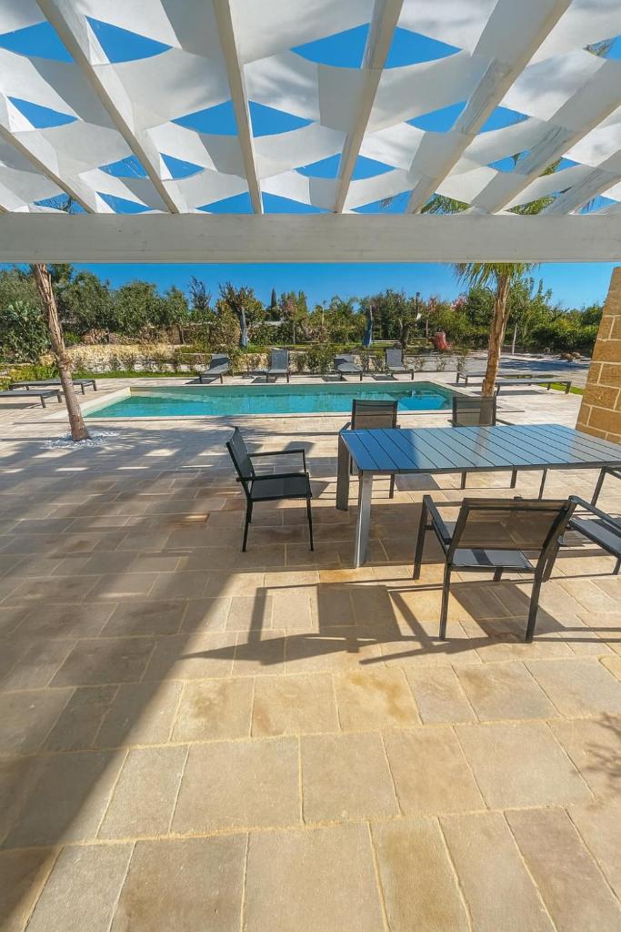une table de pique-nique et des bancs sous un pavillon avec piscine dans l'établissement Oasi Temerano, à Seclì