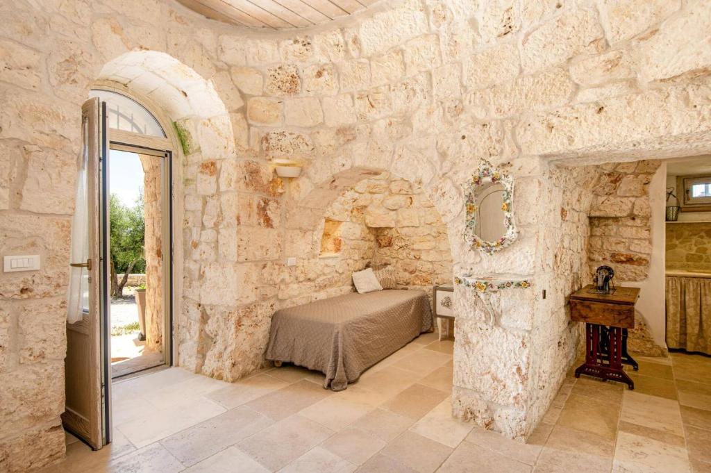 une chambre avec un lit dans un mur de pierre dans l'établissement Villa Angelo by Villa Plus, à Ostuni