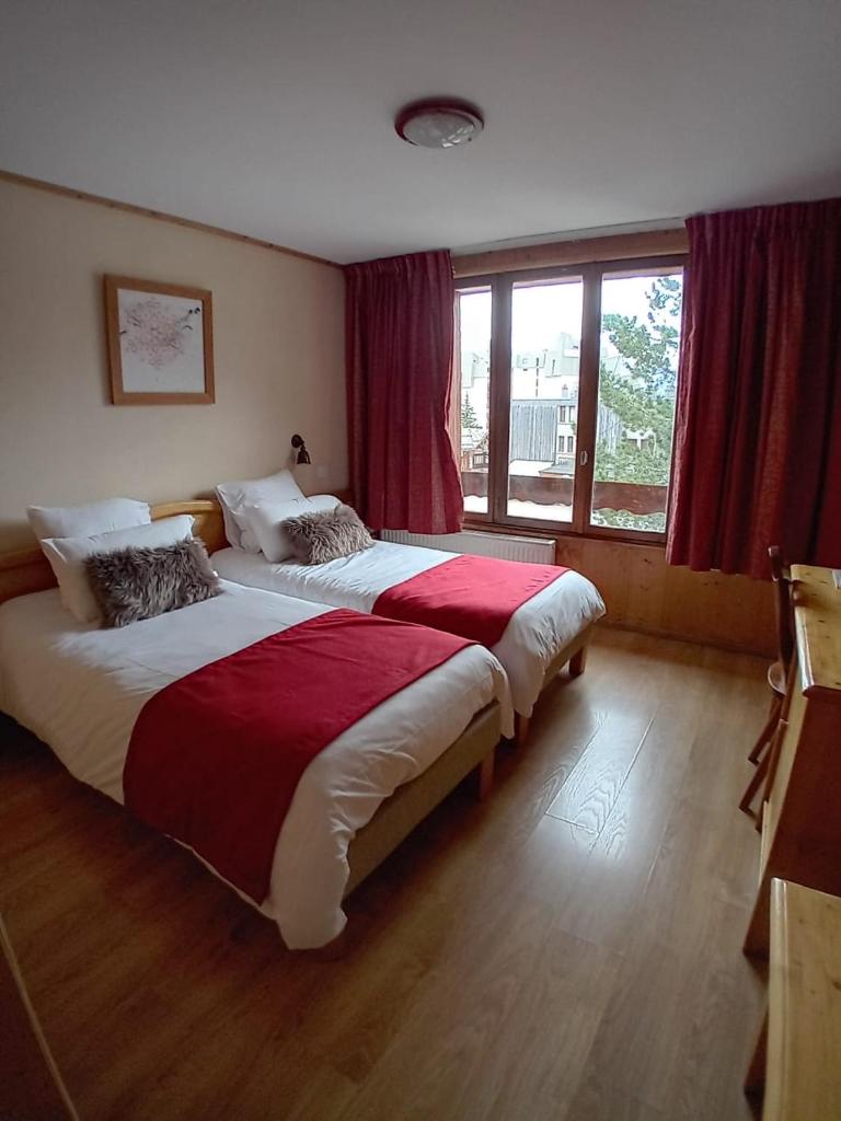 une chambre avec deux lits et une grande fenêtre dans l'établissement Hotel le Sherpa, à Les Deux Alpes