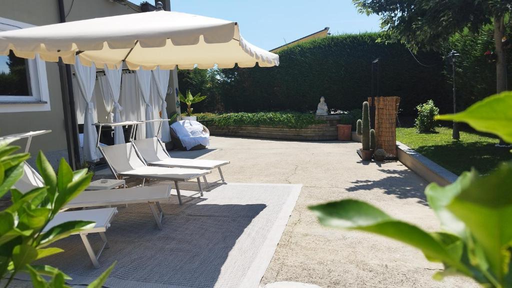 une terrasse avec des chaises blanches et un parasol dans l'établissement Country Relais Villa Margherita, à Pralormo