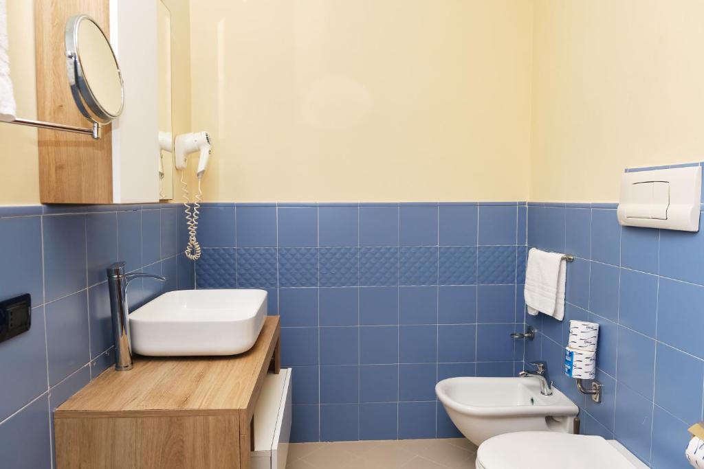 La salle de bains est pourvue de carrelage bleu, de toilettes et d'un lavabo. dans l'établissement La Isla Resort, à Pontecagnano