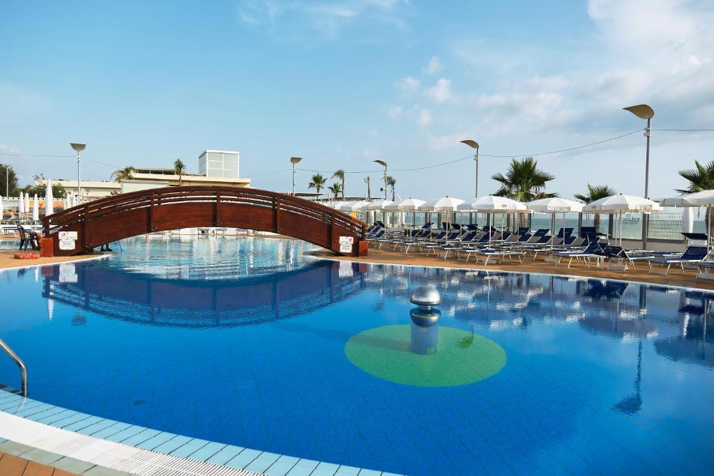 une grande piscine avec des chaises et un pont dans l'établissement La Isla Resort, à Pontecagnano