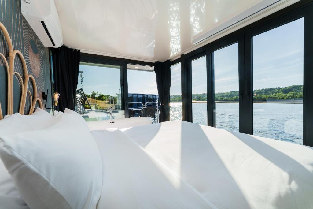 une chambre avec un lit et une vue sur l'eau dans l'établissement L'Escale Royale Saint-Martin-la-Garenne Port Ilon - Seine - Giverny, à Saint-Martin-la-Garenne