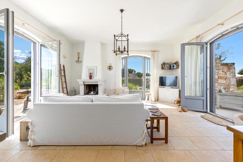 une chambre avec un grand lit et de grandes fenêtres dans l'établissement Trullo Sant`Andrea by Perle di Puglia, à Ceglie Messapica