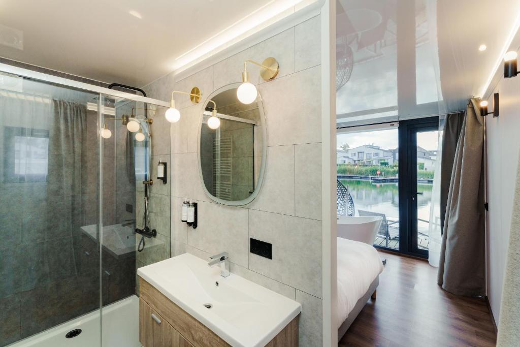 une salle de bain avec un lavabo, une douche et un miroir dans l'établissement L'Escale Royale L'Isle Adam Port - Oise, à LʼIsle-Adam