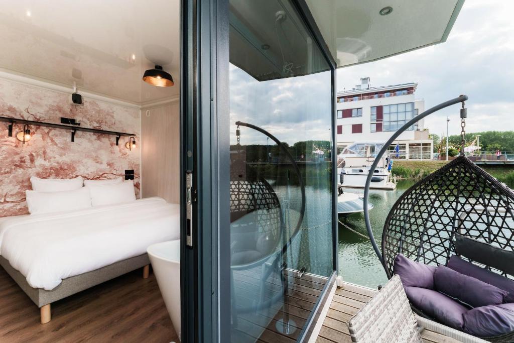 une chambre avec un lit et un balcon dans l'établissement L'Escale Royale L'Isle Adam Port - Oise, à LʼIsle-Adam