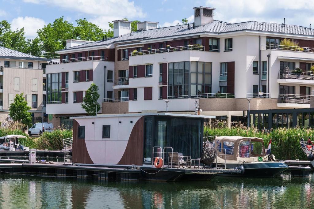 un bateau est amarré sur l'eau devant un bâtiment dans l'établissement L'Escale Royale L'Isle Adam Port - Oise, à LʼIsle-Adam