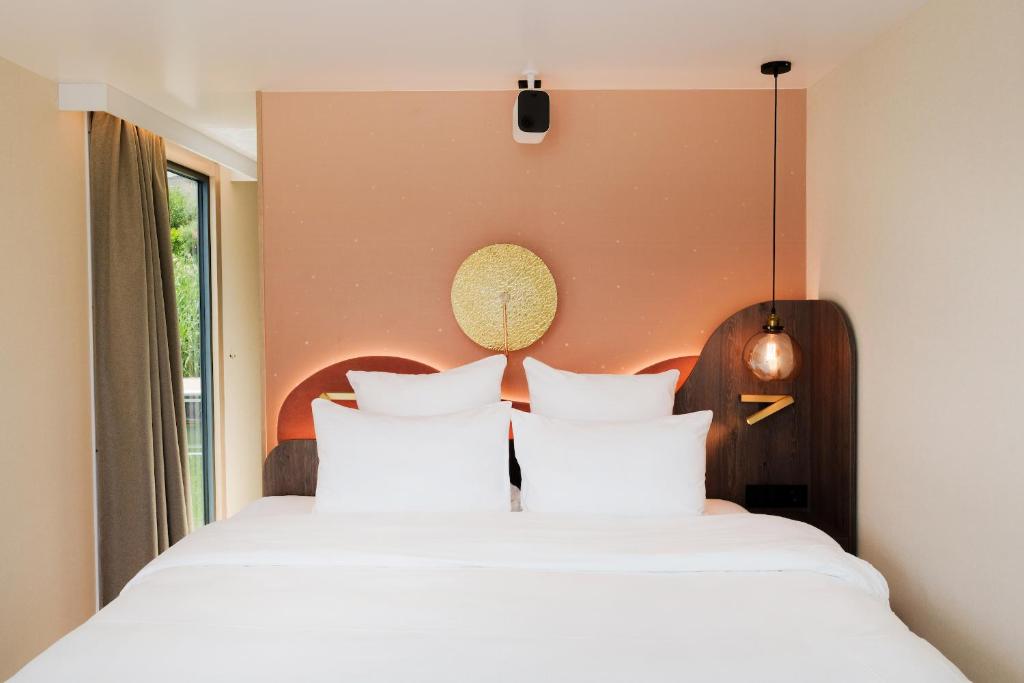 une chambre avec deux lits avec des oreillers blancs dans l'établissement L'Escale Royale L'Isle Adam Port - Oise, à LʼIsle-Adam