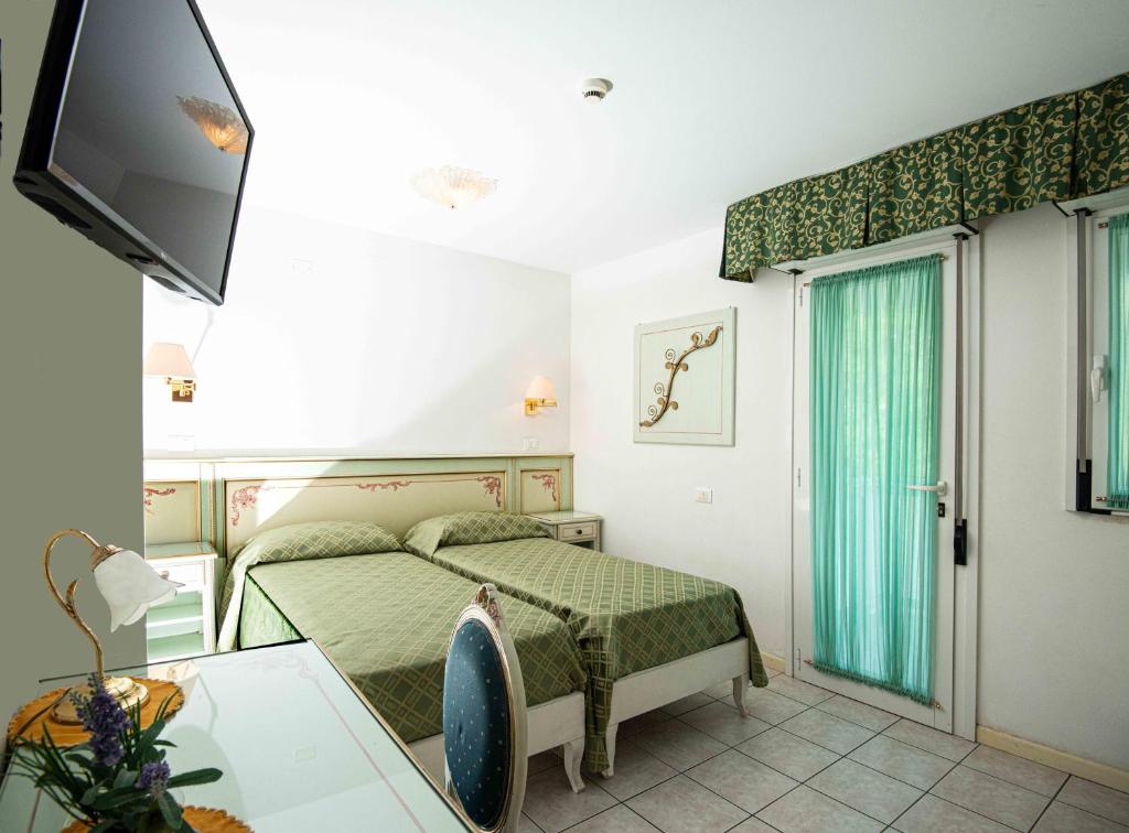 une chambre avec un lit, une table et une télévision dans l'établissement Hotel Oasi, à Lignano Sabbiadoro 56 autres photos