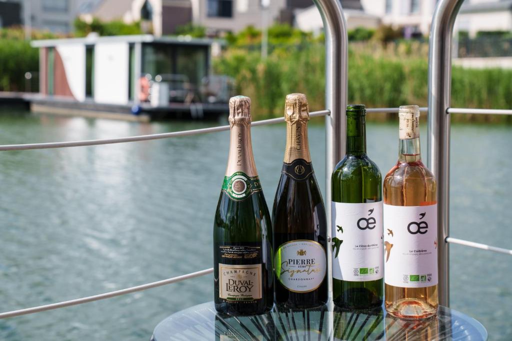 trois bouteilles de vin posées sur une table près de l'eau dans l'établissement L'Escale Royale L'Isle Adam Port - Oise, à LʼIsle-Adam