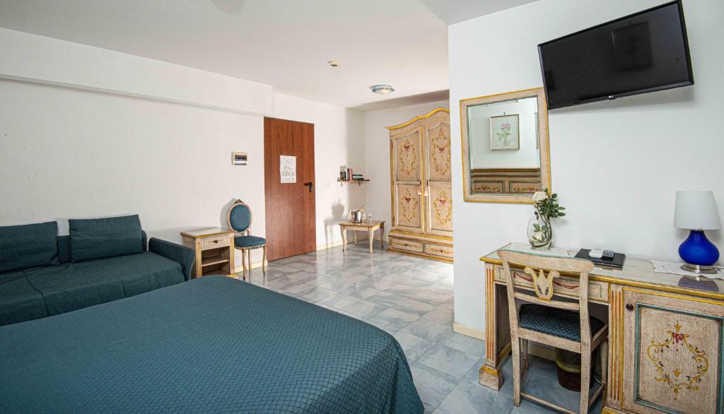 Cette chambre comprend un lit, un canapé et une télévision. dans l'établissement Hotel Oasi, à Lignano Sabbiadoro
