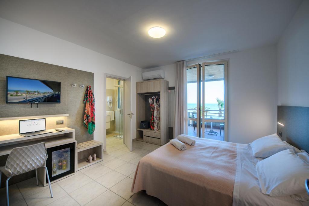 une chambre avec un lit, un bureau et une télévision dans l'établissement Hotel Graziella, à Martinsicuro