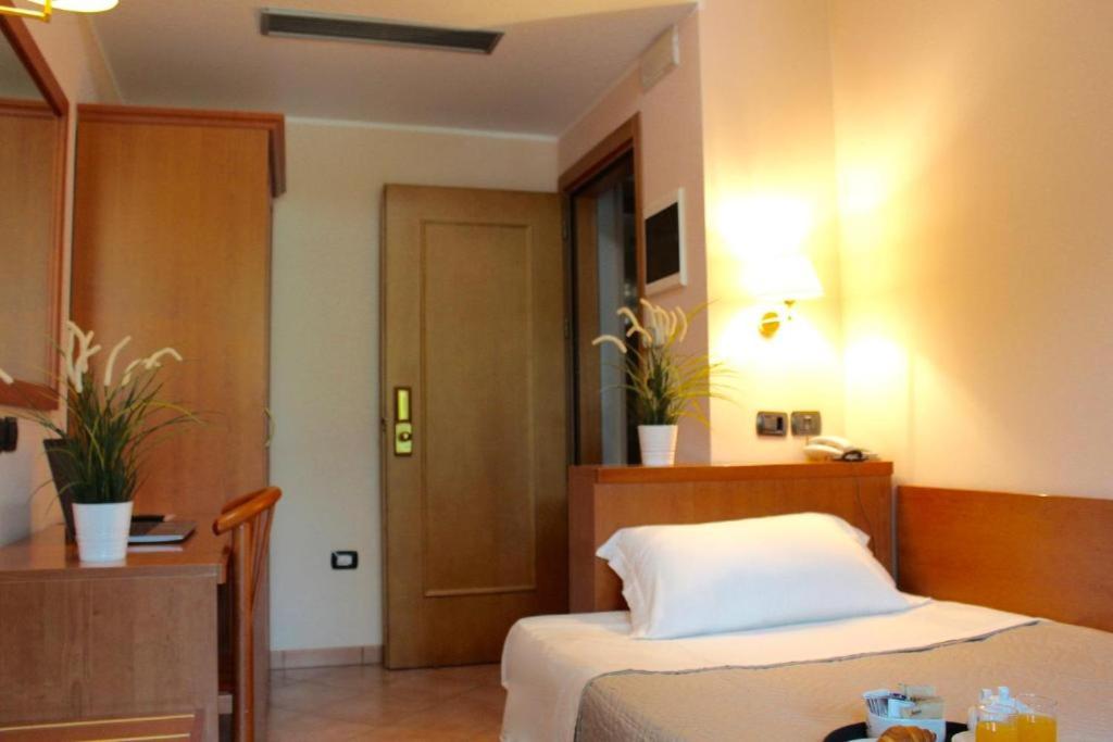 - une chambre avec un lit, une table et une porte dans l'établissement Giole Hotel, à Cesenatico
