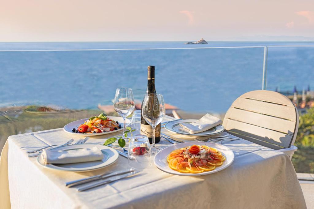 - une table avec des assiettes de nourriture et une bouteille de vin dans l'établissement Hotel Villa Ombrosa, à Portoferraio
