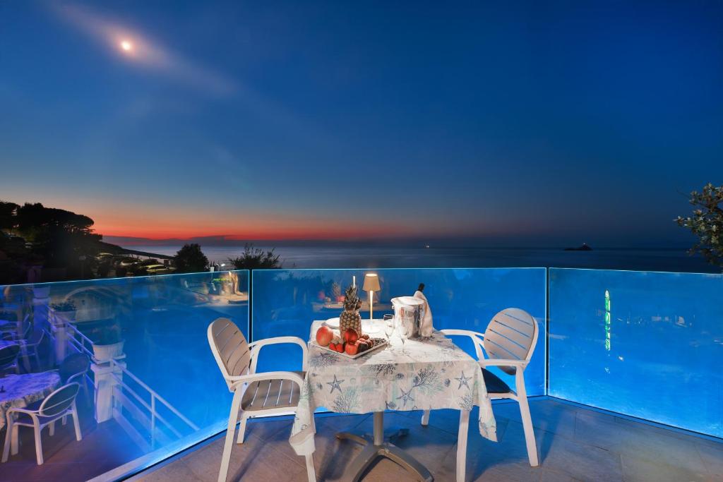 - une table et des chaises sur un balcon la nuit dans l'établissement Hotel Villa Ombrosa, à Portoferraio