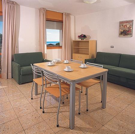 un salon avec une table, des chaises et un canapé dans l'établissement Residence Cà D'oro, à Lido di Jesolo