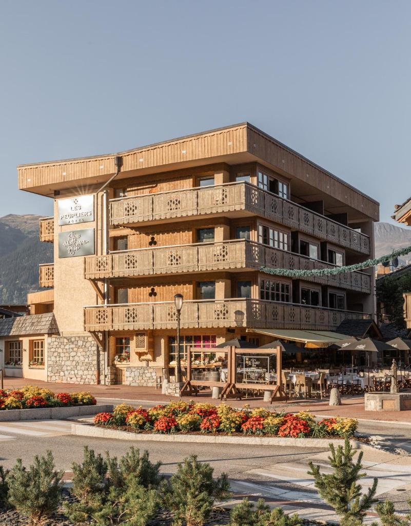 un grand bâtiment avec des fleurs devant lui dans l'établissement Hôtel Les Peupliers, à Courchevel